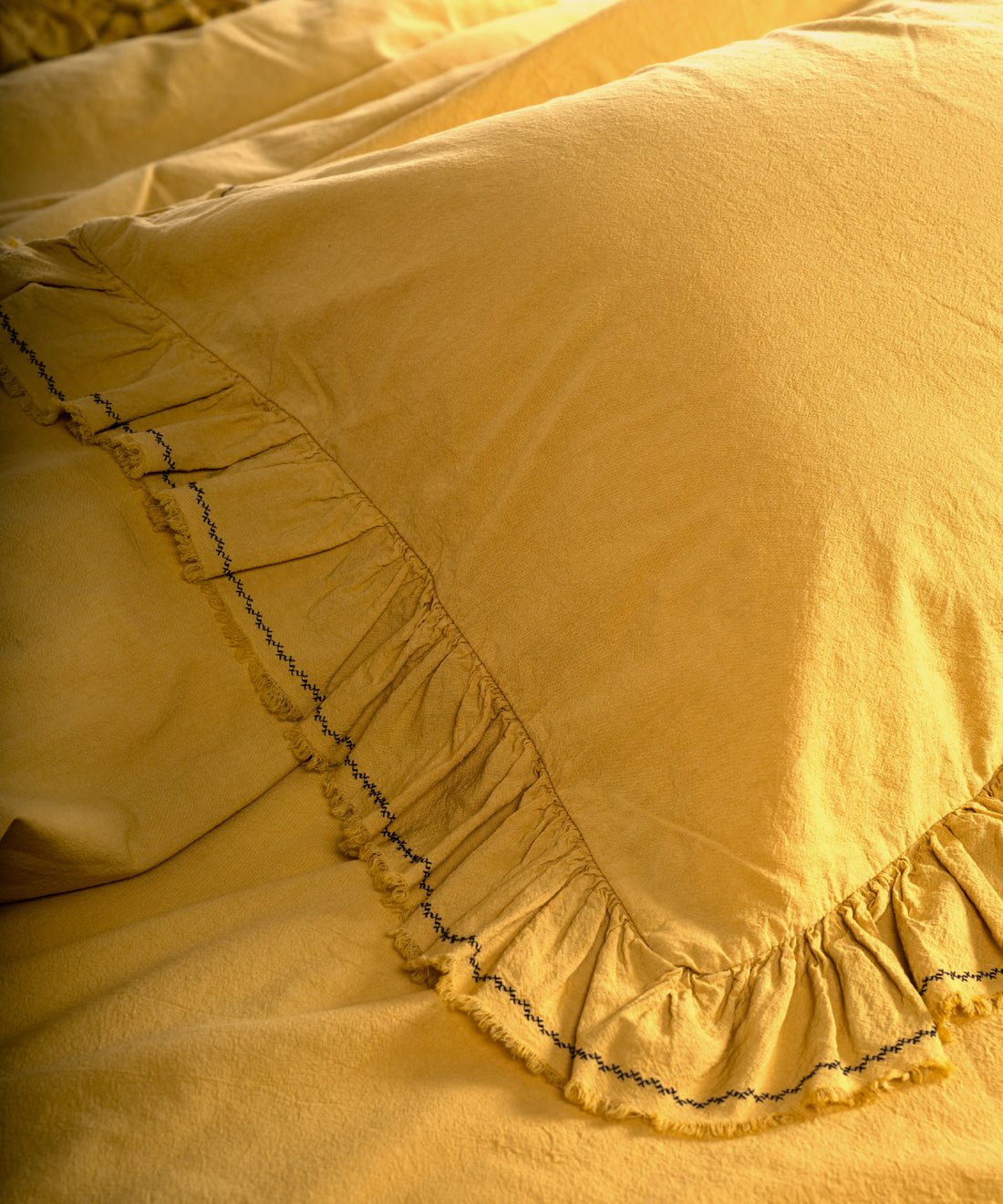 Honey renkli %100 pamuk stonewash nevresim takımı, fırfır detaylı yastık kılıfları ve minimalist nakışlı kenar tasarımıyla yatak üzerinde genel görünüm