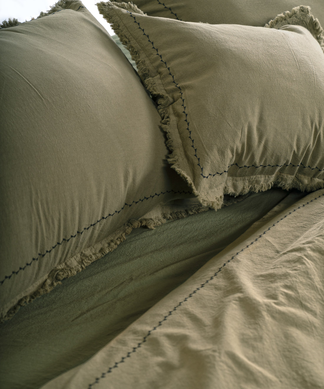 Olive renk pamuk yastık kılıfı, kapak kapamalı tasarım, saçak ve şerit nakış detaylarıyla yakın plan görünüm