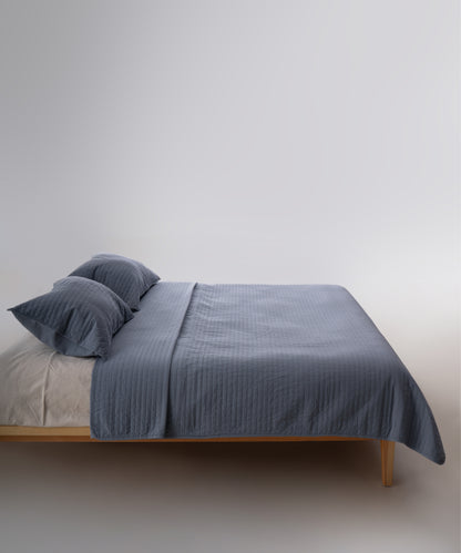 Akdeniz mavisi stonewash %100 pamuk yatak örtüsü kumaşının yumuşak ve doğal dokusu, yakın plan