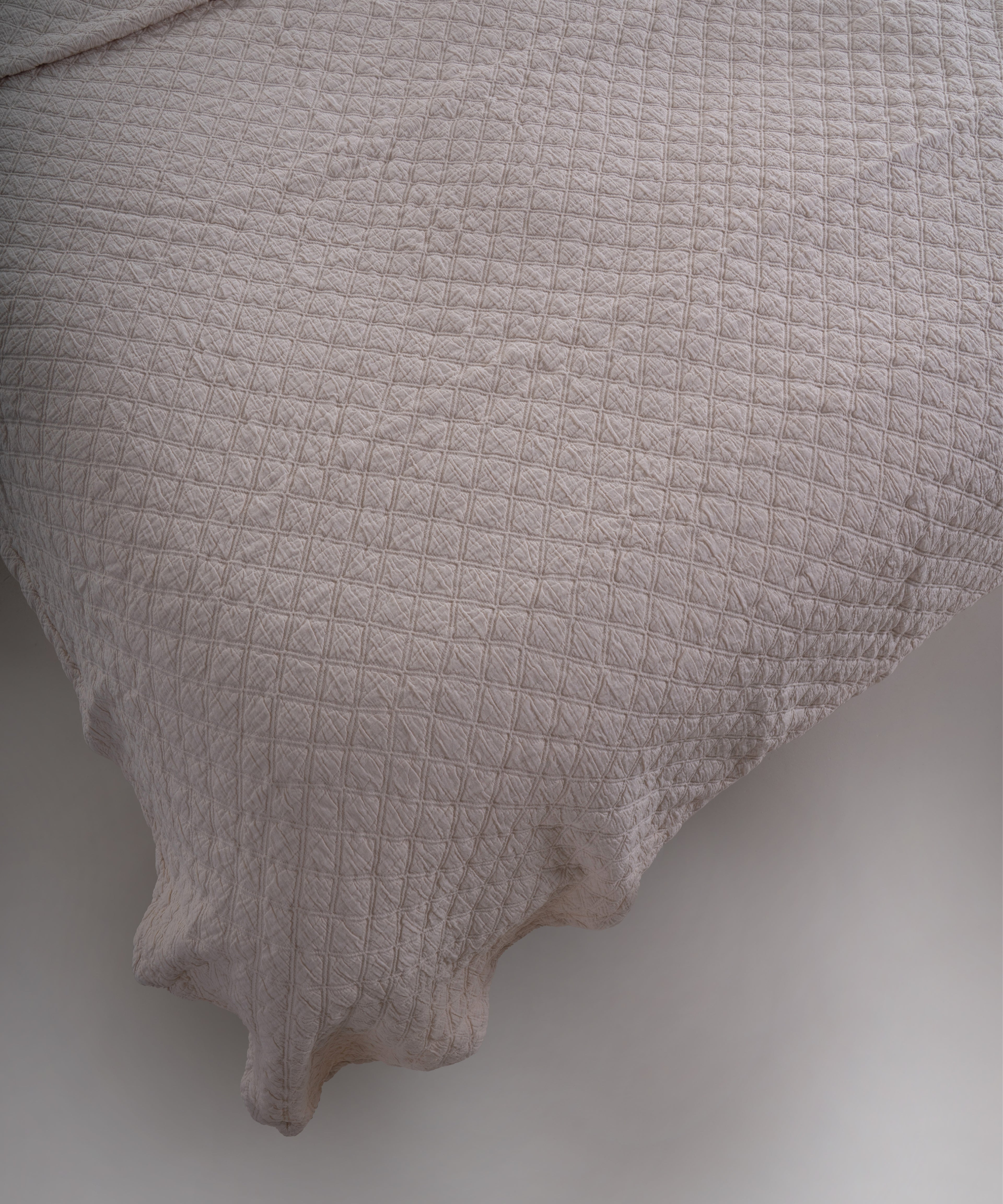 Cream renkli stonewash %100 pamuk yatak örtüsü kumaşının yumuşak ve doğal dokusu, yakın plan